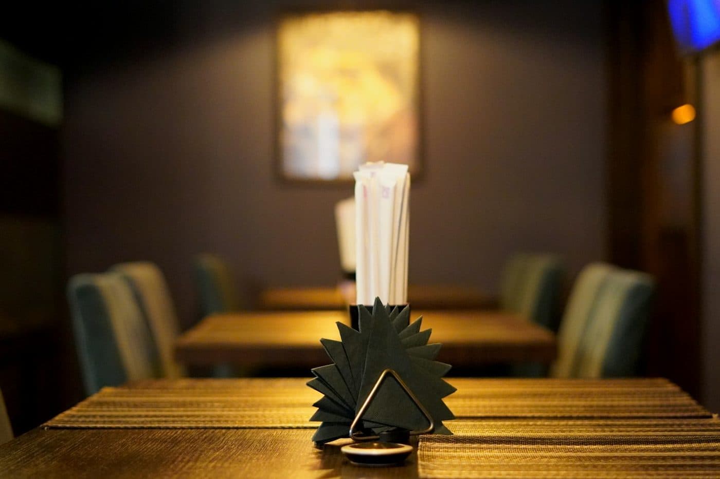 Table de restaurant avec une serviette pliée, dans une salle à la lumière chaleureuse
